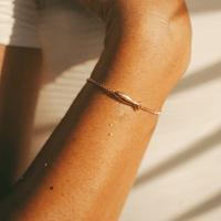 Bracelet Poisson en plaqué or, porté au poignet en extérieur